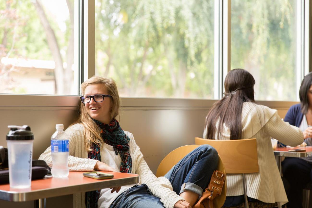 Student sitting with friend in cafe